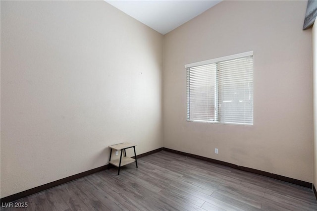 empty room featuring vaulted ceiling and hardwood / wood-style flooring