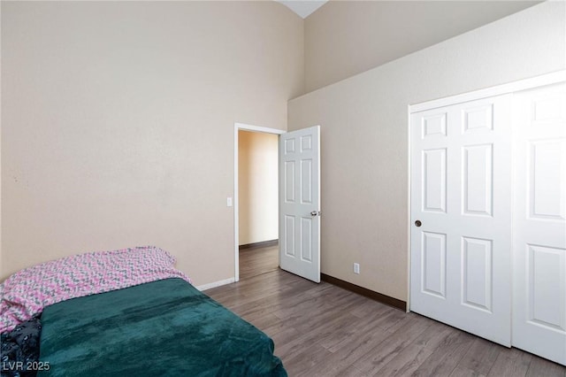 bedroom with high vaulted ceiling, a closet, and light hardwood / wood-style floors