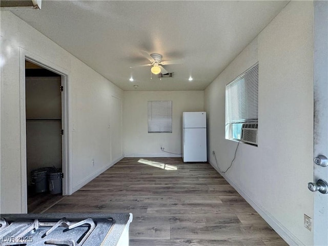 interior space with ceiling fan, white refrigerator, and light hardwood / wood-style flooring