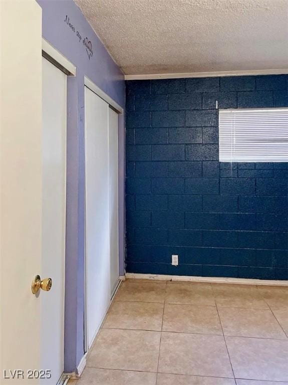 unfurnished room with a textured ceiling and light tile patterned floors