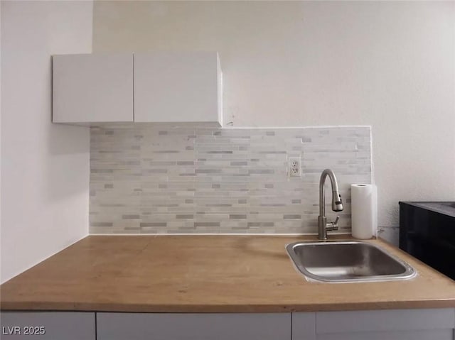 details featuring sink, white cabinets, and decorative backsplash