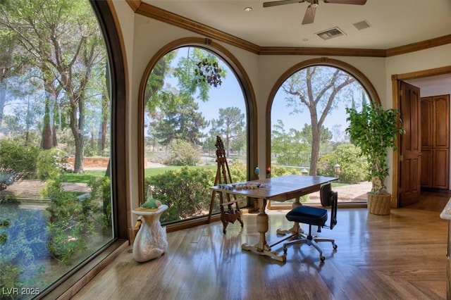 interior space with ornamental molding, wood finished floors, visible vents, and a ceiling fan