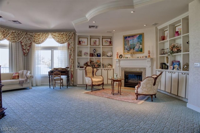 living area featuring a premium fireplace, built in features, carpet, and crown molding