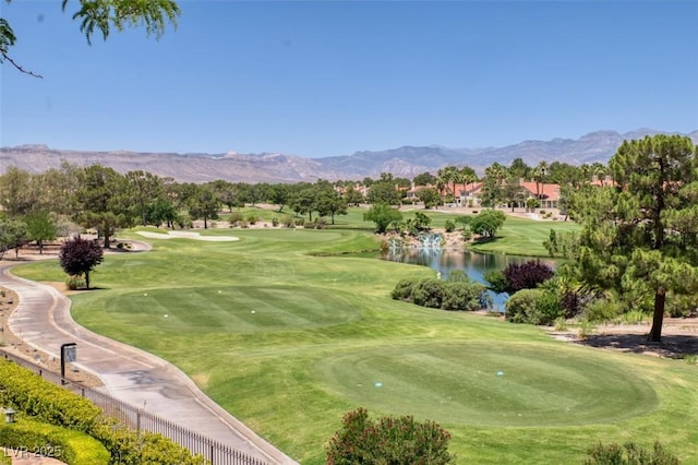 view of community featuring a yard, golf course view, and a water and mountain view