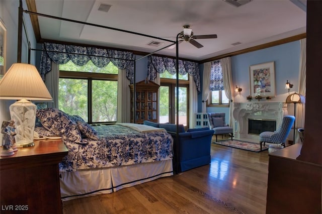 bedroom featuring a fireplace, visible vents, wood finished floors, and ornamental molding