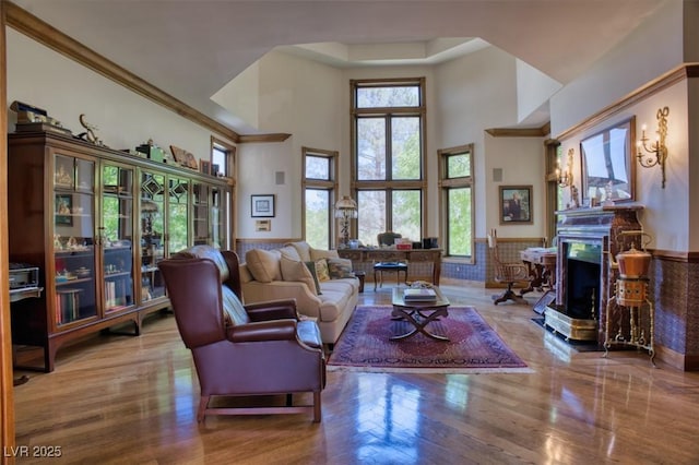 living room with a high end fireplace, wood-type flooring, a towering ceiling, and a wealth of natural light