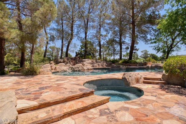 view of swimming pool featuring pool water feature and an in ground hot tub