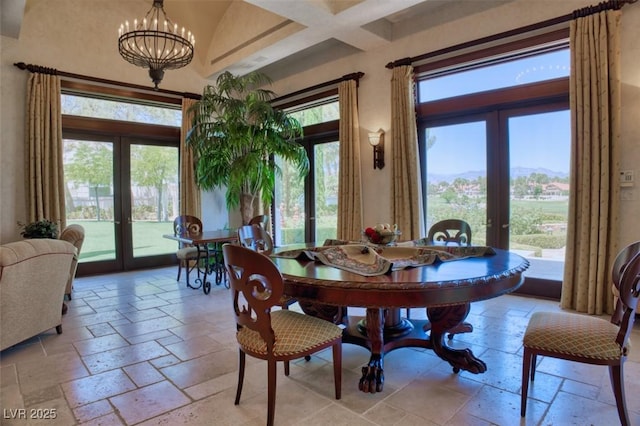 dining space with stone tile flooring, french doors, a healthy amount of sunlight, and an inviting chandelier