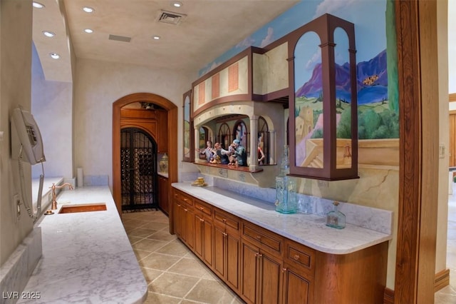 bar featuring arched walkways, a sink, visible vents, and recessed lighting