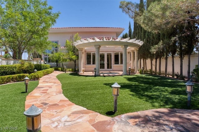 rear view of house featuring fence, a yard, french doors, a pergola, and stucco siding