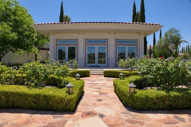 rear view of property featuring french doors, a tile roof, and stucco siding