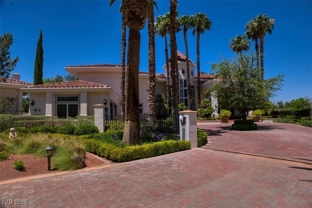 view of front facade with a tile roof, fence, and stucco siding