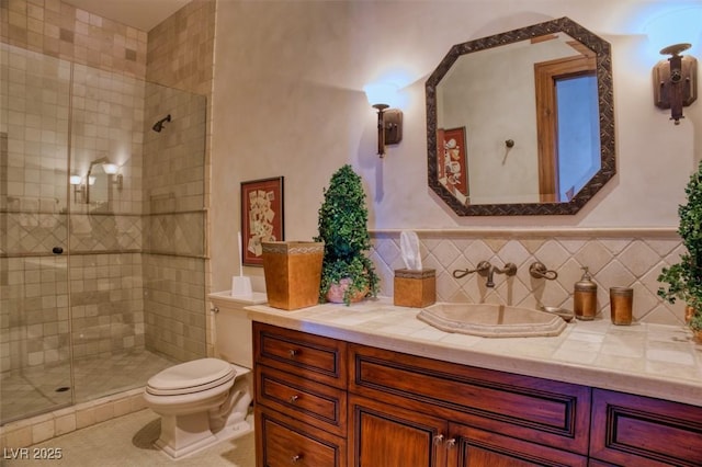 bathroom with toilet, vanity, a shower with shower door, and backsplash