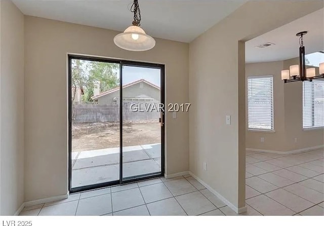 entryway with an inviting chandelier, light tile patterned floors, and a healthy amount of sunlight