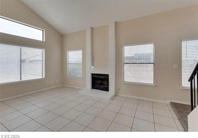 unfurnished living room featuring lofted ceiling, a brick fireplace, and light tile patterned flooring