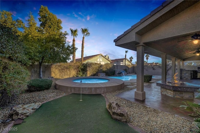 pool at dusk featuring ceiling fan and a patio