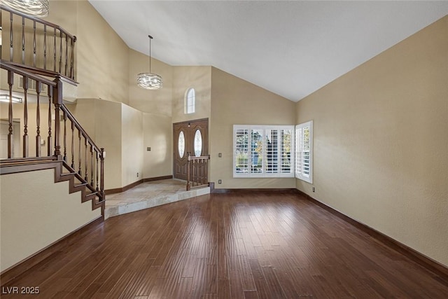 entryway with high vaulted ceiling, an inviting chandelier, and wood-type flooring