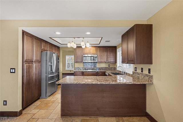 kitchen featuring sink, decorative light fixtures, kitchen peninsula, decorative backsplash, and appliances with stainless steel finishes