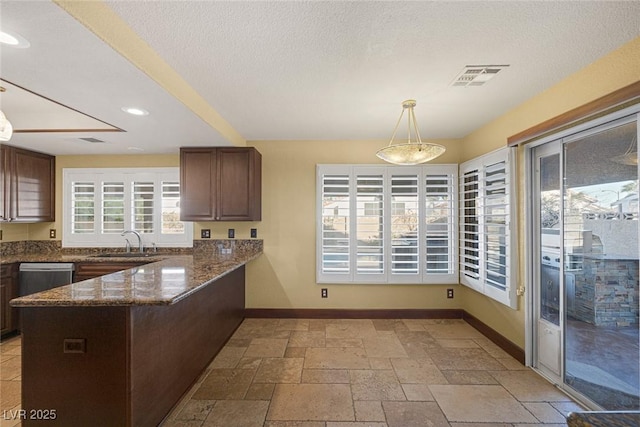 kitchen featuring sink, dishwasher, dark stone countertops, kitchen peninsula, and pendant lighting