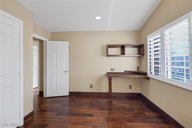 unfurnished office featuring dark wood-type flooring and built in desk