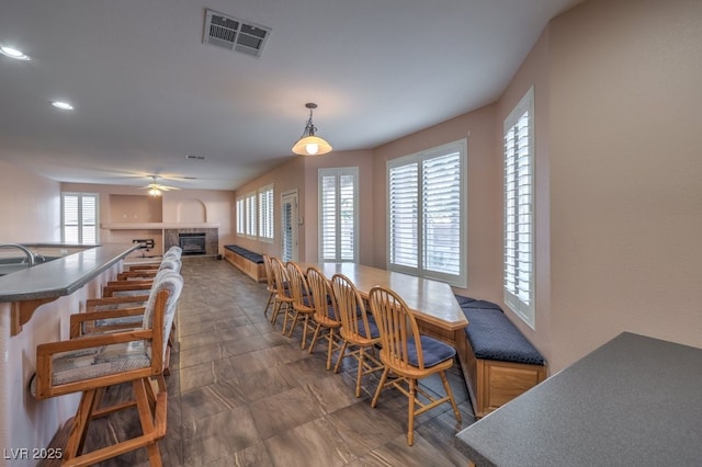 dining room featuring a fireplace, ceiling fan, and a healthy amount of sunlight