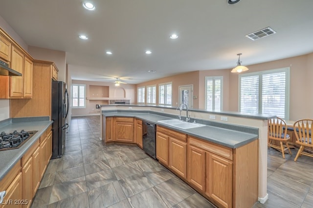 kitchen with decorative light fixtures, a center island with sink, black appliances, ceiling fan, and sink