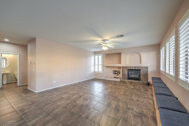 unfurnished living room featuring ceiling fan and a fireplace