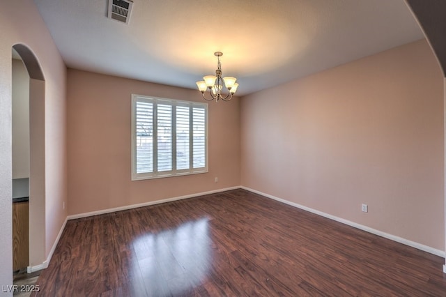 empty room with an inviting chandelier and dark wood-type flooring