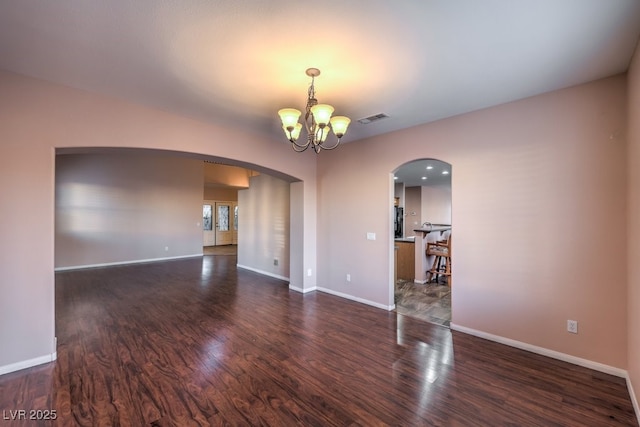 empty room featuring a notable chandelier and dark hardwood / wood-style floors