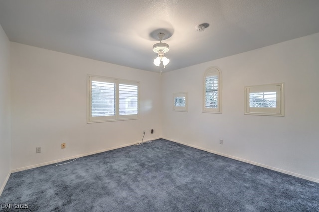 spare room featuring plenty of natural light and dark colored carpet