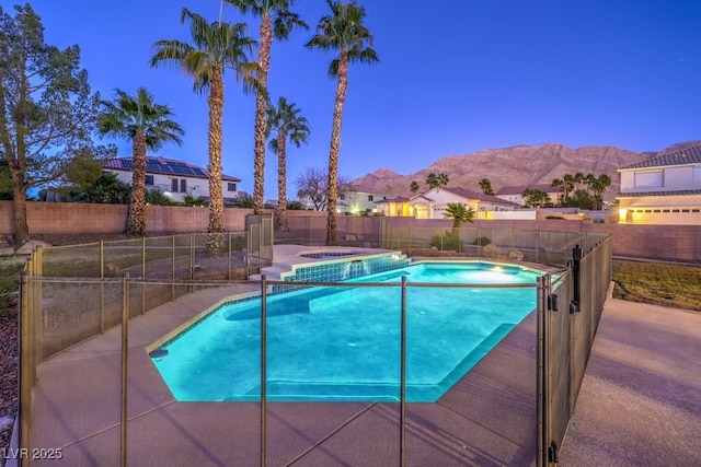 pool at dusk featuring an in ground hot tub and a mountain view