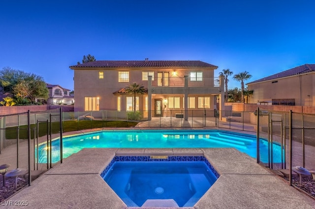 pool at dusk with an in ground hot tub