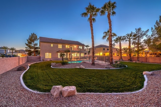 yard at dusk featuring a balcony and a fenced in pool