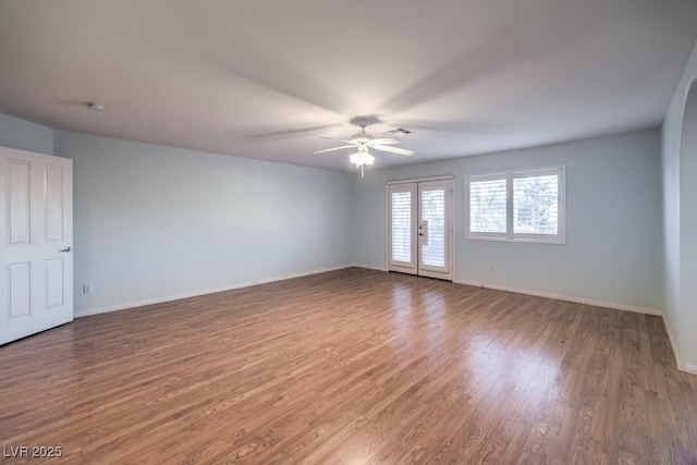 empty room featuring ceiling fan, dark hardwood / wood-style flooring, and french doors