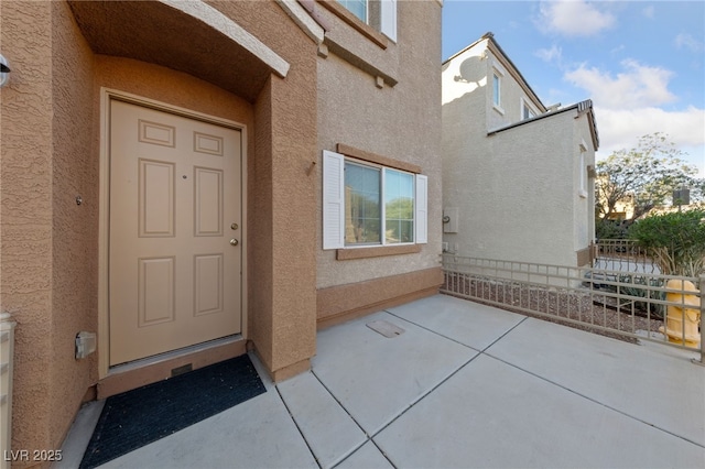 view of exterior entry featuring a patio and stucco siding