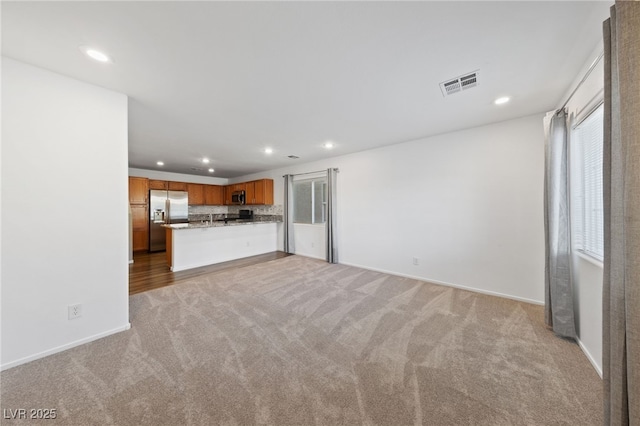 unfurnished living room with light carpet, baseboards, visible vents, and recessed lighting