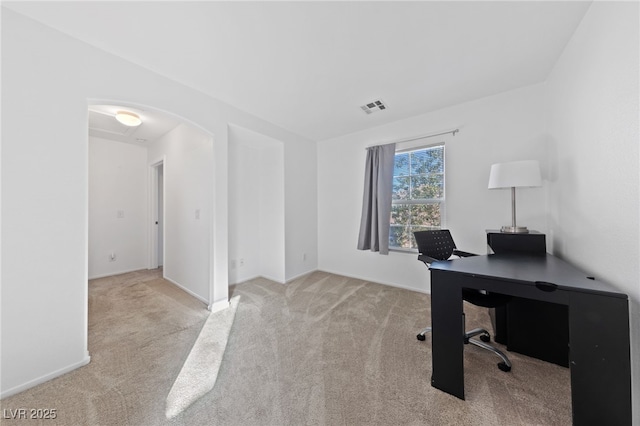 home office featuring baseboards, visible vents, arched walkways, and light colored carpet