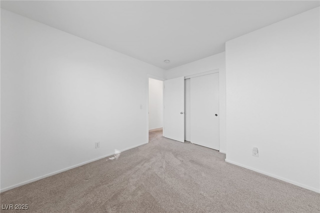 unfurnished bedroom with light carpet, baseboards, and a closet