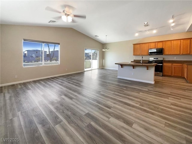 kitchen with a kitchen island with sink, a breakfast bar area, stainless steel range, dark hardwood / wood-style flooring, and ceiling fan with notable chandelier