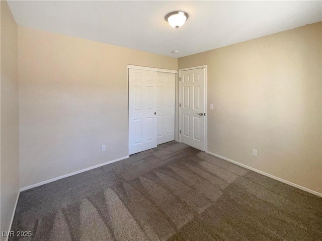 unfurnished bedroom with a closet and dark colored carpet