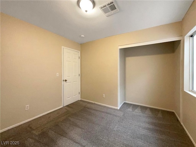 unfurnished bedroom featuring a closet and dark carpet