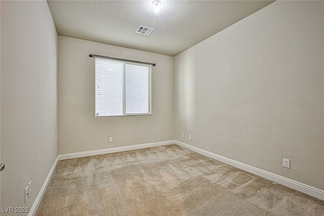 empty room featuring a textured ceiling and light carpet