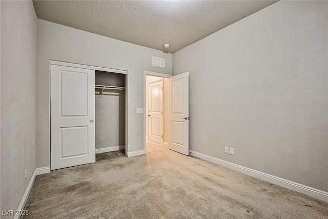 unfurnished bedroom with light colored carpet, a closet, and a textured ceiling