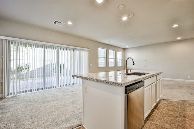 kitchen with sink, white cabinets, dishwasher, light stone counters, and an island with sink