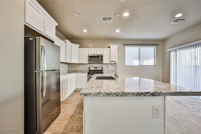 kitchen with sink, white cabinetry, light stone countertops, a kitchen island with sink, and appliances with stainless steel finishes