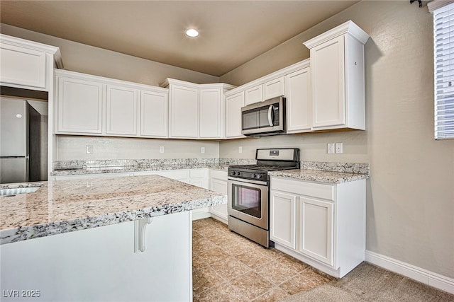 kitchen featuring white cabinets, appliances with stainless steel finishes, light stone countertops, and a kitchen breakfast bar