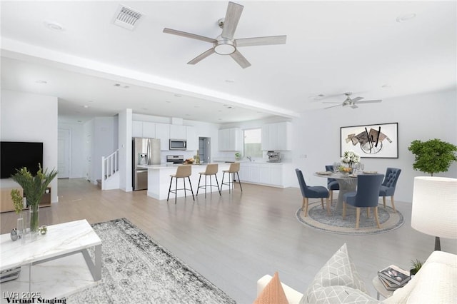 living room featuring ceiling fan, light hardwood / wood-style floors, and sink