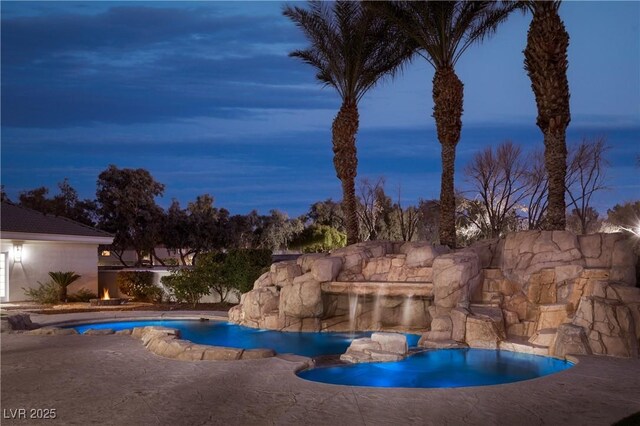 pool at dusk with a patio area