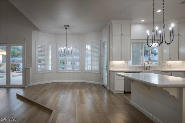 kitchen featuring a notable chandelier, white cabinets, decorative light fixtures, stainless steel dishwasher, and sink