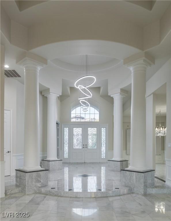 entryway with a high ceiling, french doors, and a chandelier